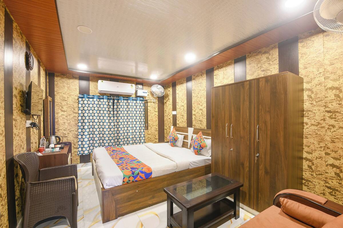 Un dormitorio con cama, armario, mesita de noche y una pequeña zona de estar.
