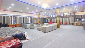 Un grand hall doté de plusieurs espaces de détente, d’une scène et d’un comptoir d’accueil.
