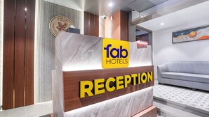 Una reception con un cartello 'fab hotels' e la scritta 'RECEPTION'.
