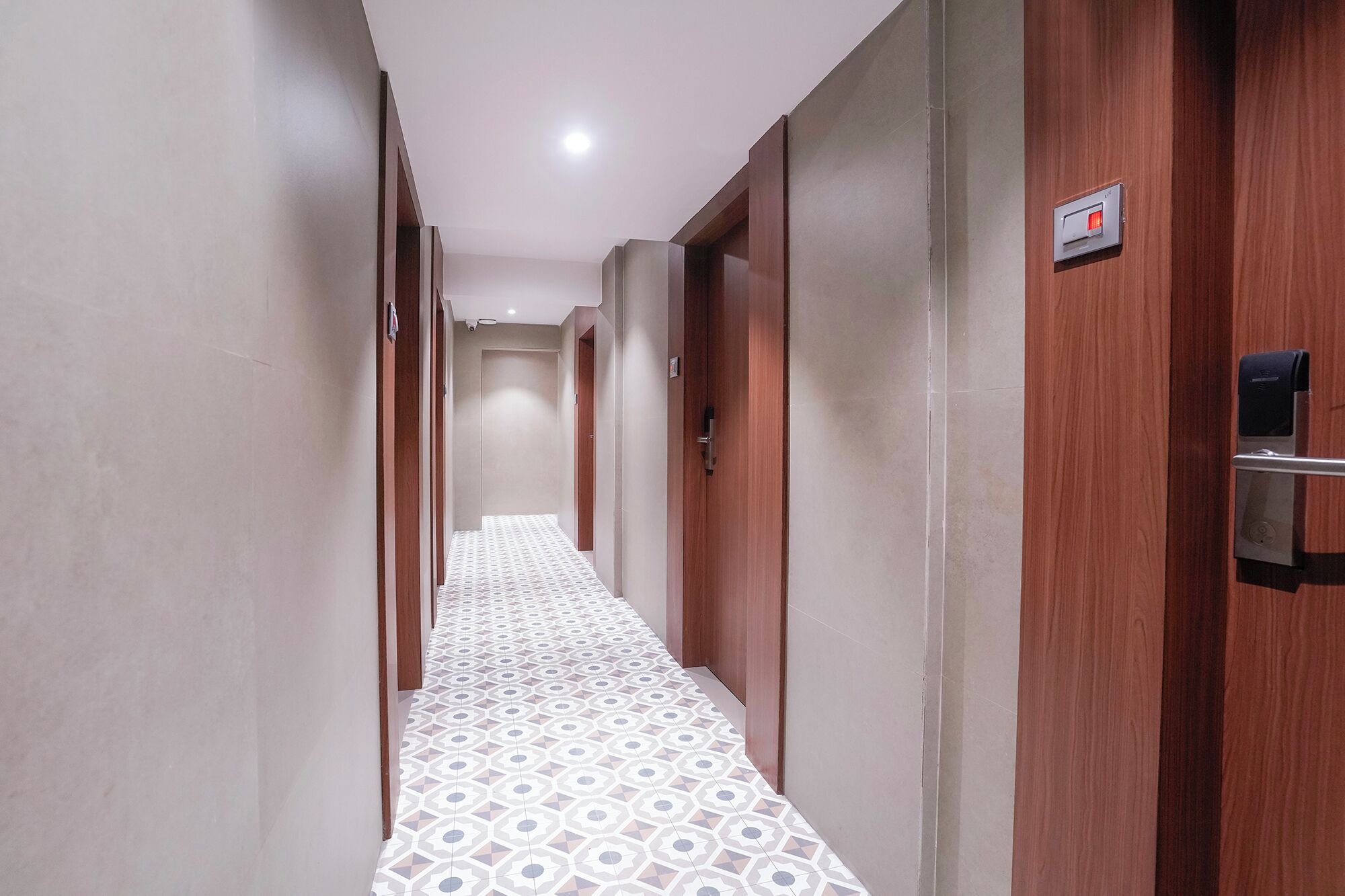 Ein Hotelgang mit gemusterten Bodenfliesen, Holztüren und einem Gegensprechanlage-System.