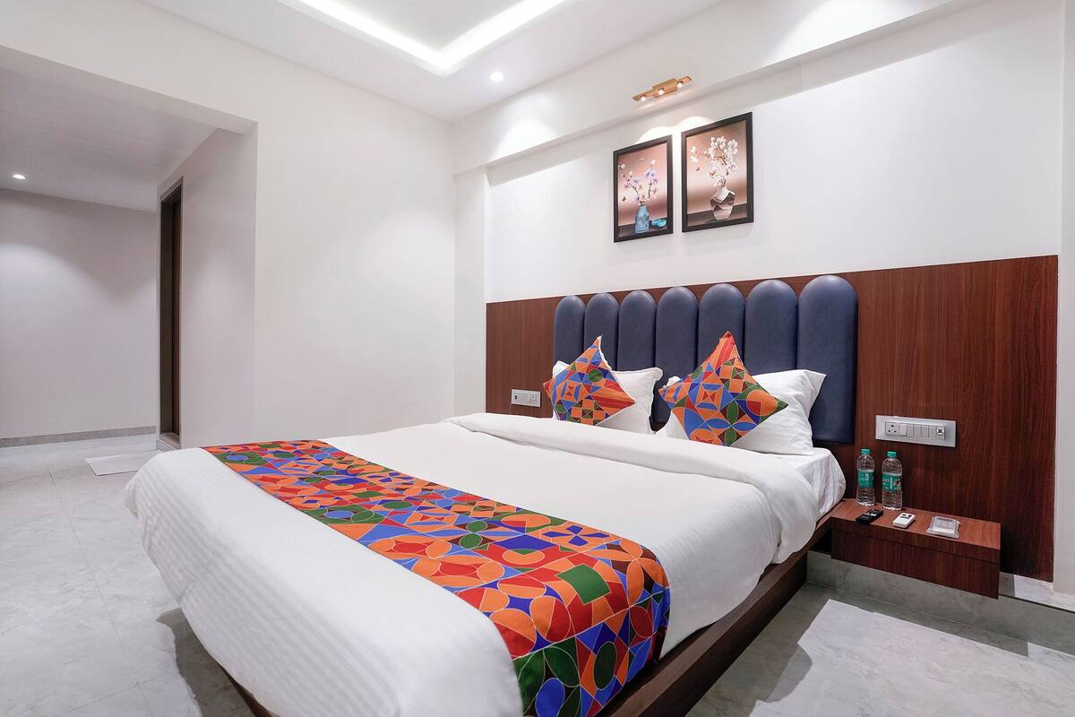 Ein modernes Hotelzimmer mit einem großen Bett, einem Holzkopfteil und zwei an der Wand befestigten Kunstwerken.