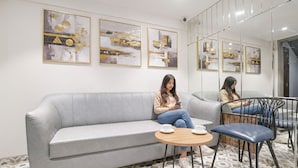 Un'area lounge moderna con un divano grigio, un tavolino rotondo in legno e una poltrona blu.
