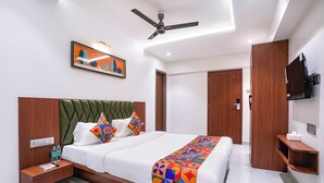 Una camera d'albergo moderna con un letto grande, una ventola a soffitto, un quadro e una TV fissata al muro.