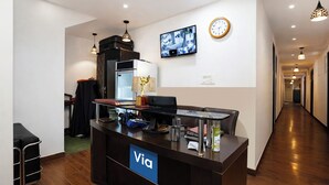 Una taquilla de recepció amb un senyal que diu 'Via', un rellotge i una càmera de seguretat a la paret.