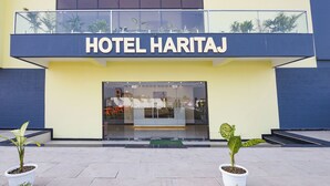 The exterior of Hotel Haritaj with a modern design, large windows, and potted plants in front. - Fabhotel Haritaj (Varanasi)