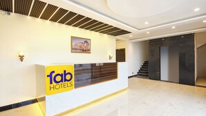 A hotel reception area with a modern design, including a reception desk, a framed picture on the wall, and a staircase leading to another floor. - Fabhotel Haritaj (Varanasi)