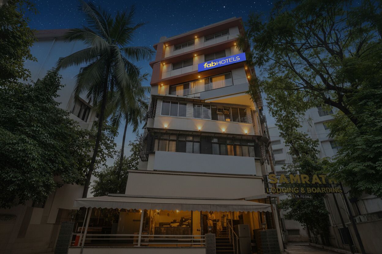 A multi-story building with a 'fabHOTELS' sign, a 'SAMRAT' sign, and a 'Lodging & Boarding' sign.
