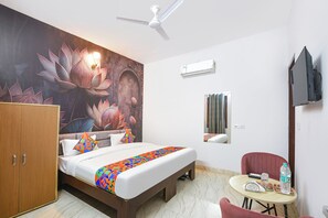 A hotel room with a bed, a wardrobe, a ceiling fan, an air conditioning unit, a television, and a small table with a chair. - Fabhotel As Residency I (Ludhiana)