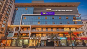 A multi-story building with a 'fabHOTELS' sign, 'DR DAVE EYE HOSPITAL' above, and various storefronts including 'Hotel Galic' and 'UHIVA'. - Fabhotel Elixir Inn (Surat)