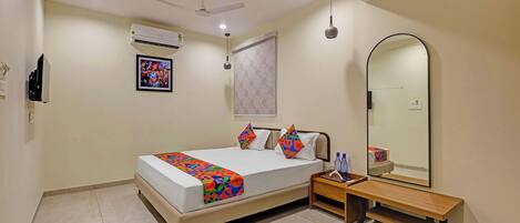 A bedroom with a bed, bedside table, mirror, and ceiling fan.