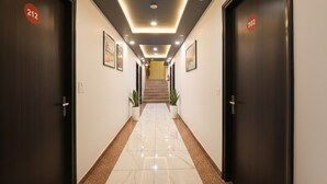 Corredor de hotel com portas numeradas 212 e 202, que dão para uma escadaria.