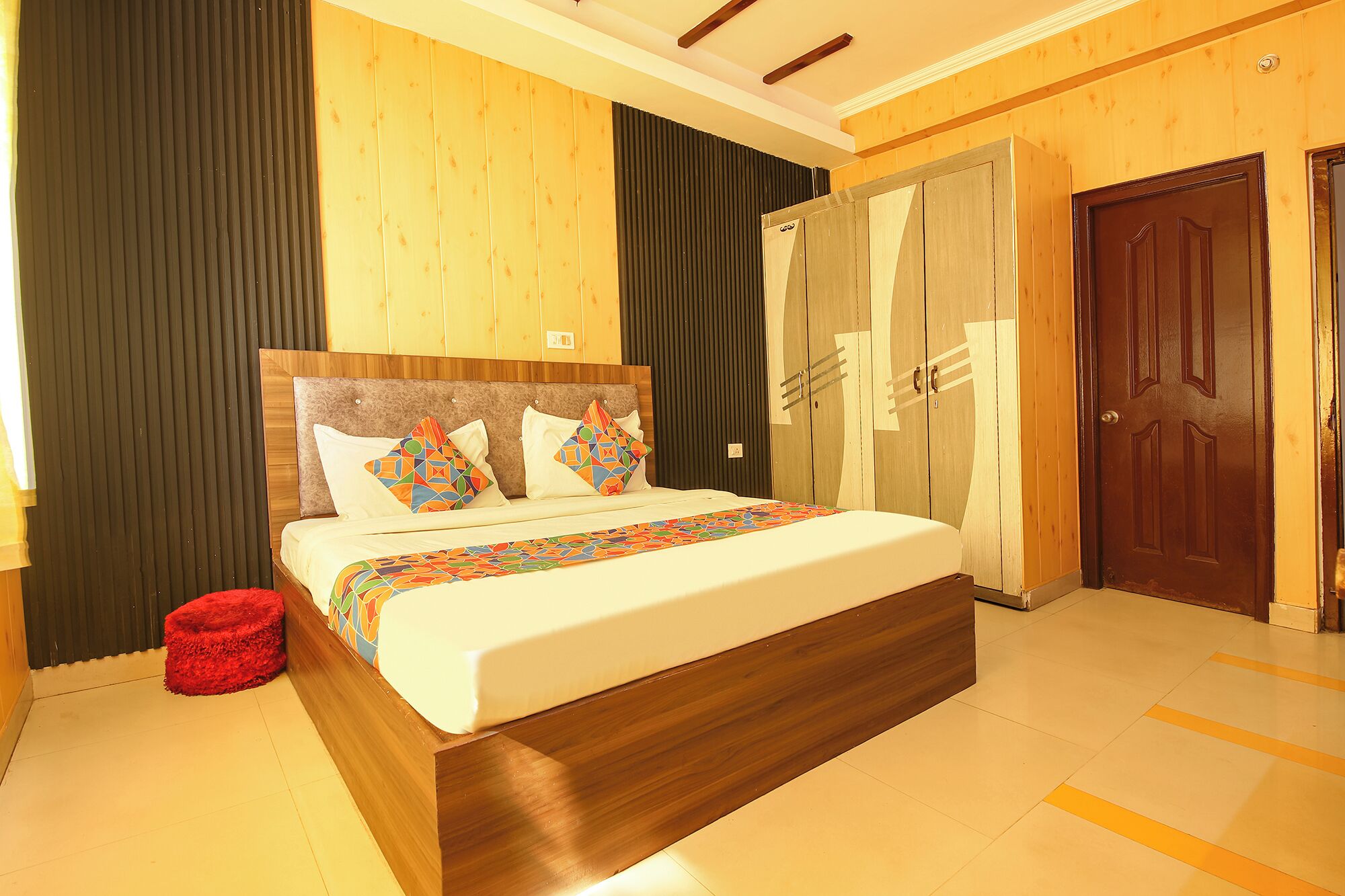 Habitación de hotel con una cama grande, cabecero de madera y un armario con espejo.