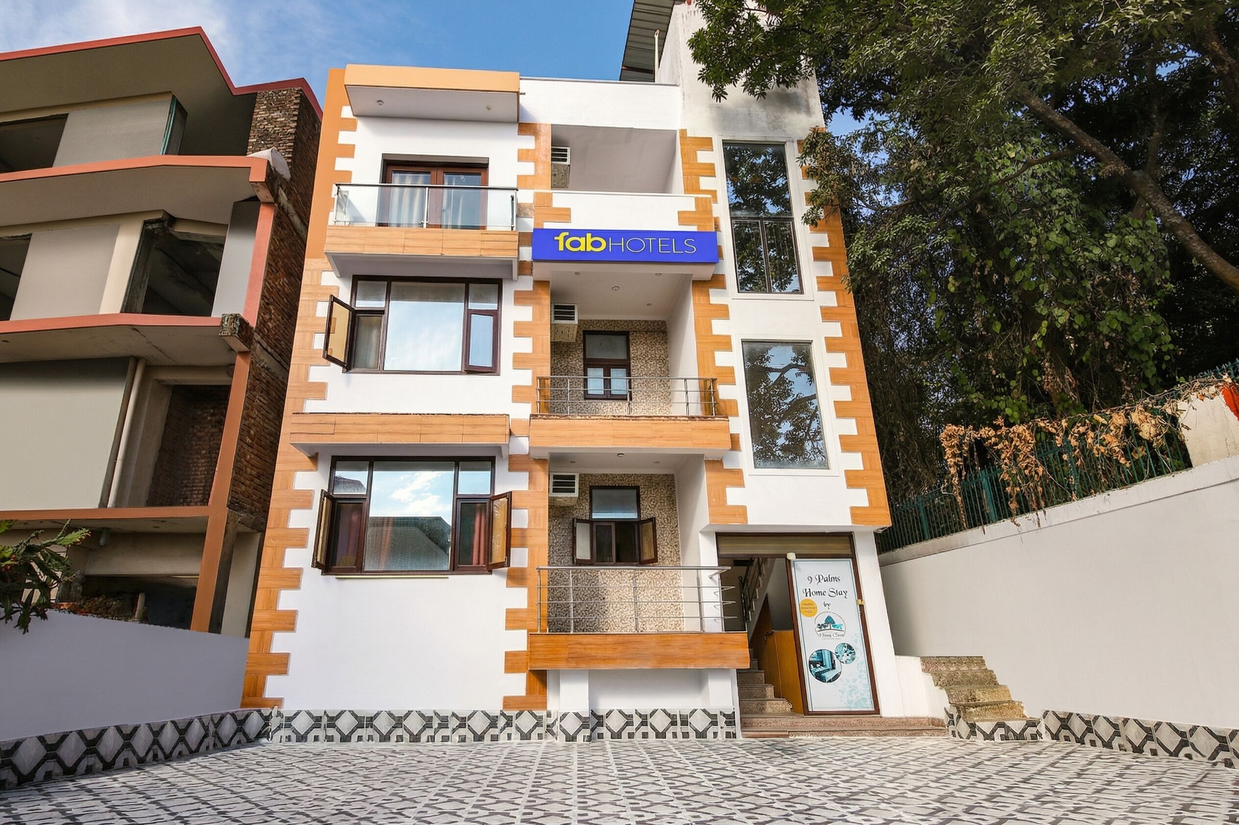 A multi-story building with a sign for 'fab hotels' and a poster advertising '9 Pines Home Stay.'
