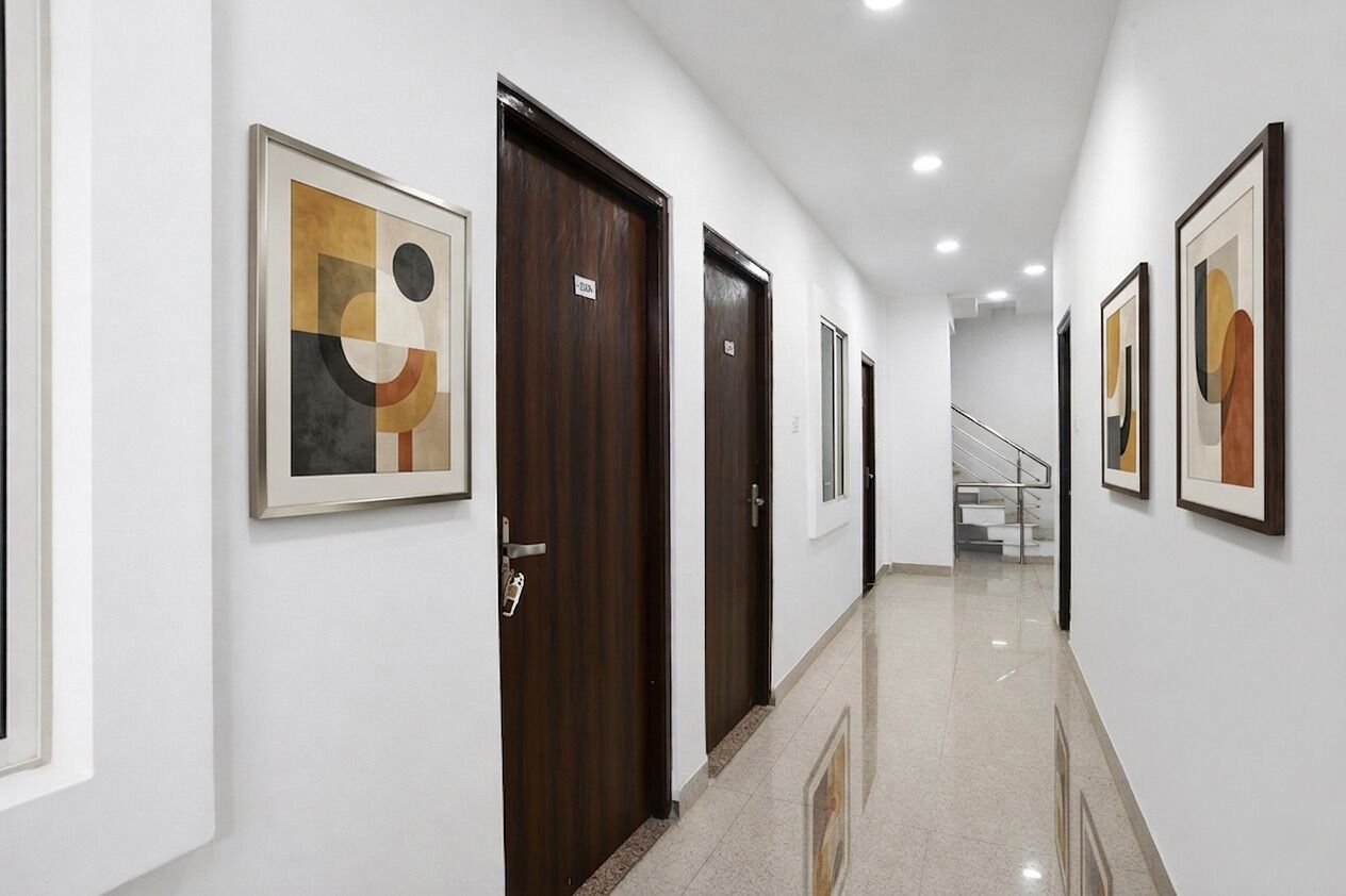 A hallway with framed abstract art, wooden doors, and a staircase in the background.