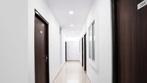 Un couloir propre et bien éclairé, avec des portes en bois foncé et des murs blancs.