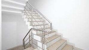 Un escalier moderne avec une rampe en métal et des marches en granit.