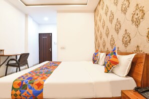 A hotel room with a bed, a desk, and a chair. - Fabhotel Shivay (Indore)