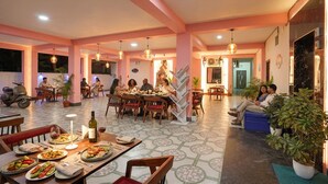 A dining area with multiple tables, chairs, and a mix of indoor and outdoor seating. - Fabhotel Golden Suites Near Puri Beach (Puri)