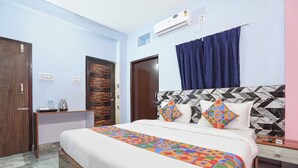 A hotel room with a bed, a nightstand, an air conditioning unit, and a bathroom door. - Fabhotel Golden Suites Near Puri Beach (Puri)