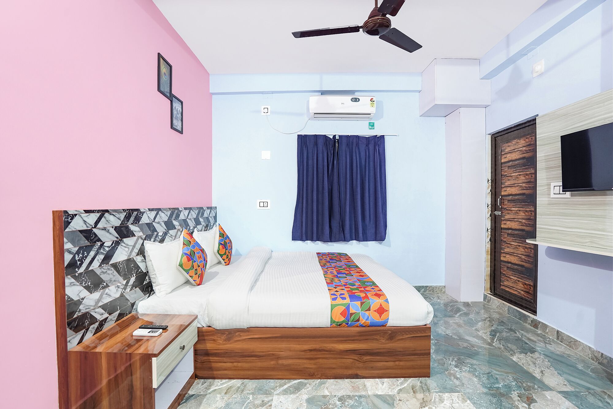 A bedroom with a bed, a nightstand, a ceiling fan, an air conditioner, a window with curtains, and a door.