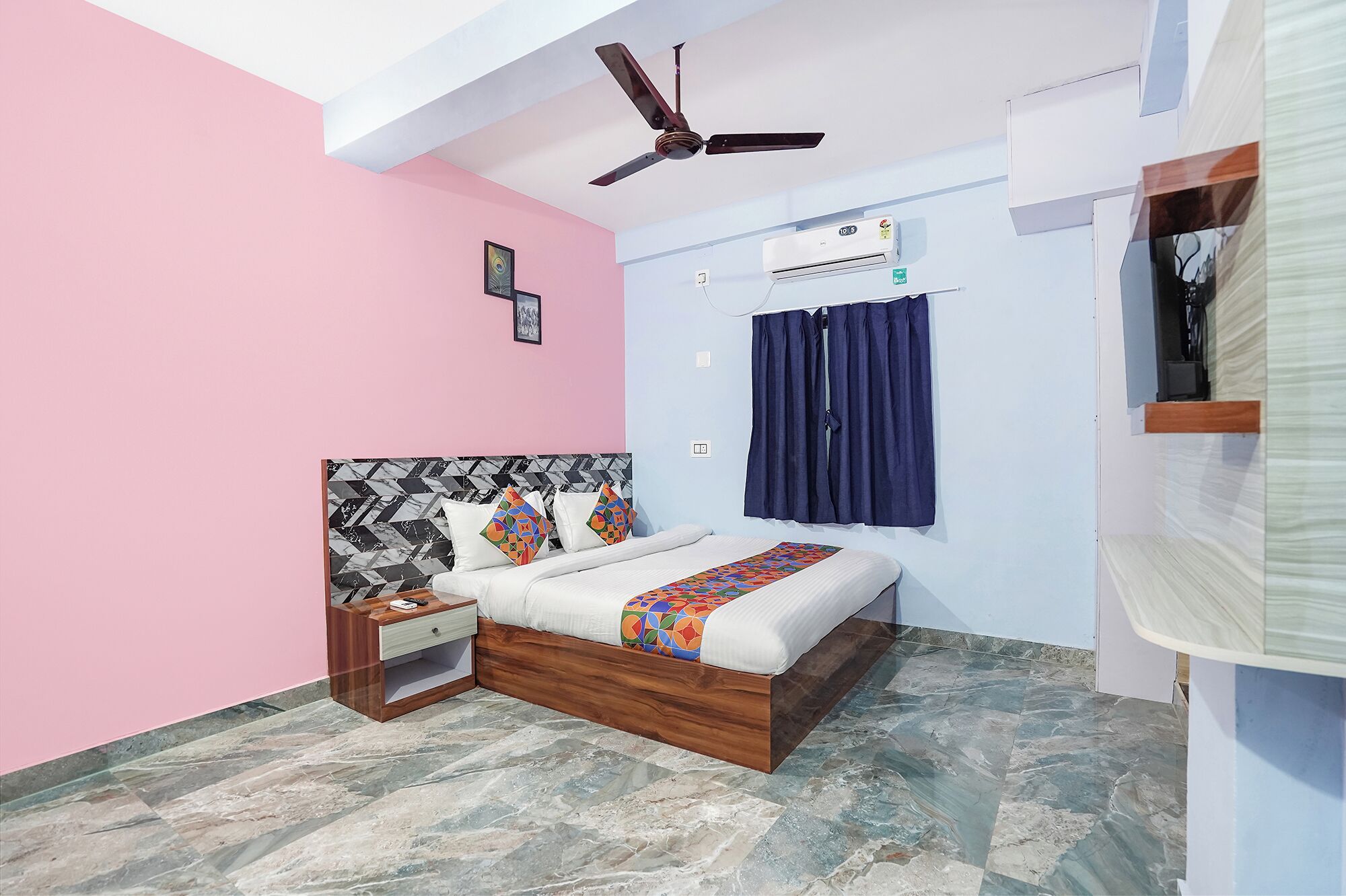A bedroom with a bed, nightstand, ceiling fan, air conditioning unit, and a window with curtains.