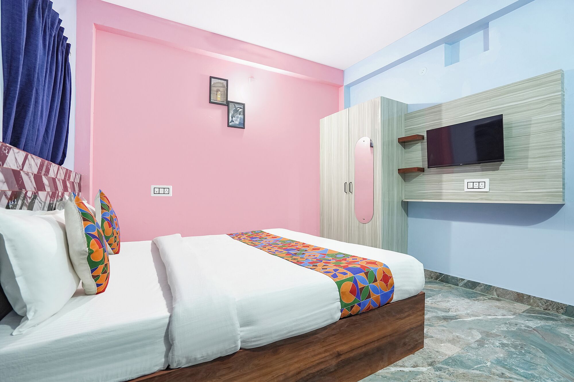 A bedroom with a bed, a TV mounted on the wall, and a wardrobe.