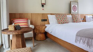 A hotel room with a wooden headboard, a bedside table with a basket and remote control, a bed with patterned pillows, and a wall-mounted light fixture. - Old River Story Long'an Inn (Mianyang)