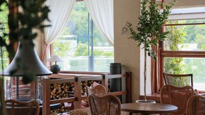 A cozy room with wicker furniture, a round table, and a large window with curtains. - Old River Story Long'an Inn (Mianyang)
