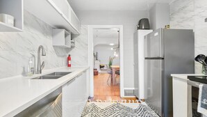 Une cuisine moderne avec des meubles blancs, un réfrigérateur en acier inoxydable et un pare-feu en marbre.