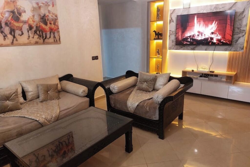 Un salon avec deux canapés, une table basse, un téléviseur fixé au mur et une cheminée.