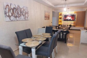 A dining area with a glass table, woven placemats, and modern chairs. - Spacious 120 m² apartment - Downtown | IPTV - Wi-Fi - Netflix (Kenitra)