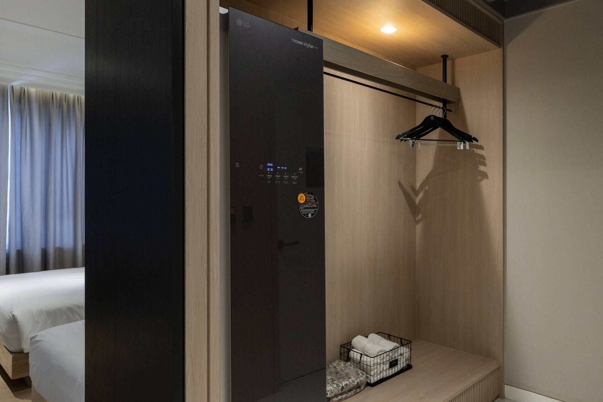Una habitación de hotel moderna con un armario de color oscuro, un banco de madera y una percha para ropa.