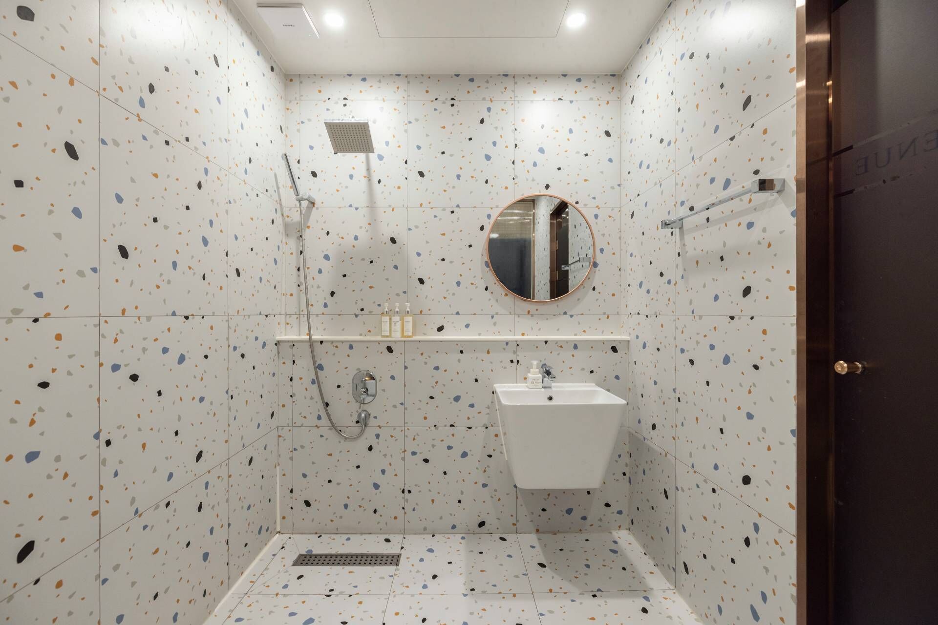 A small, modern bathroom with a shower, a sink, and a mirror.