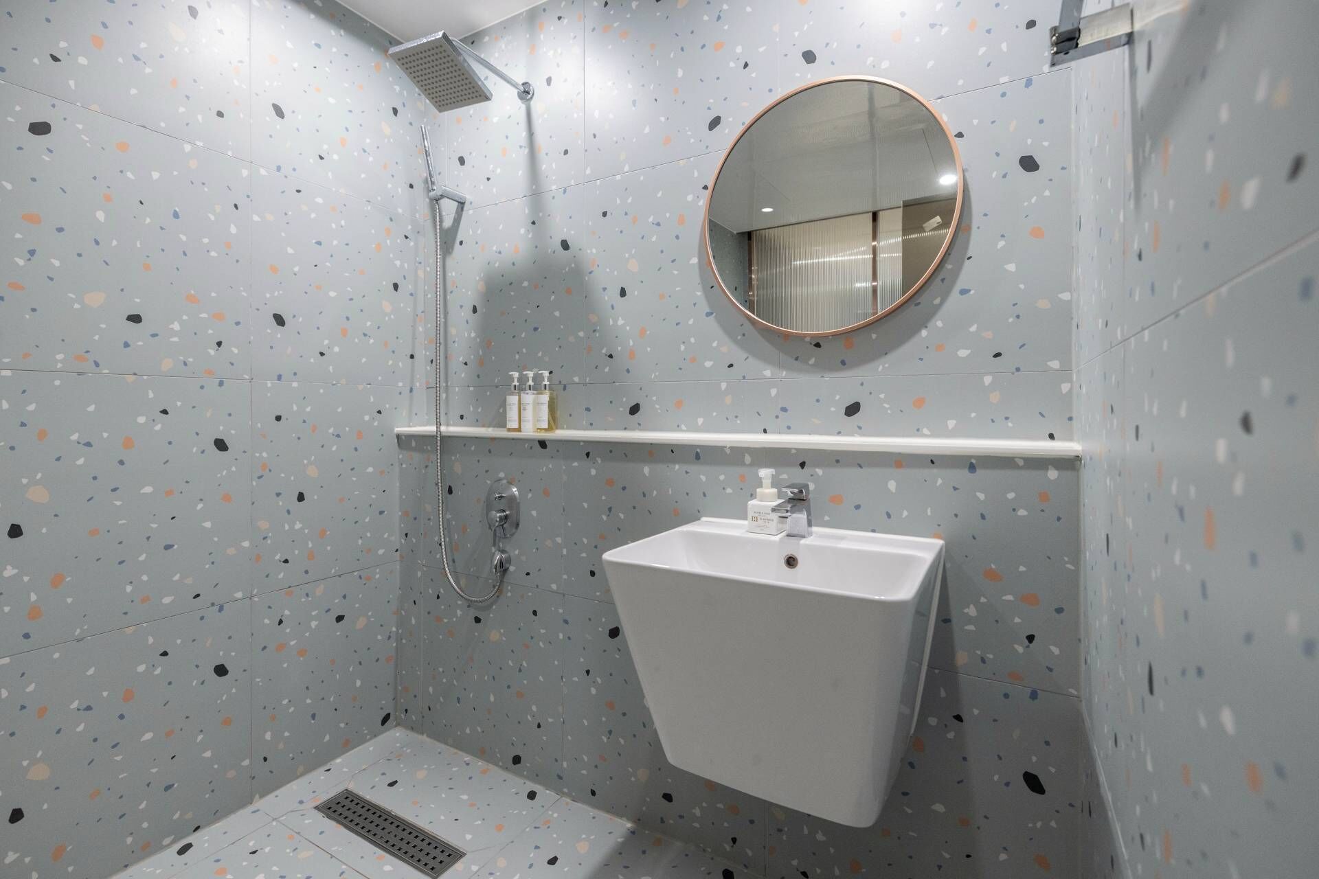 A modern bathroom with a shower, a sink, and a mirror.