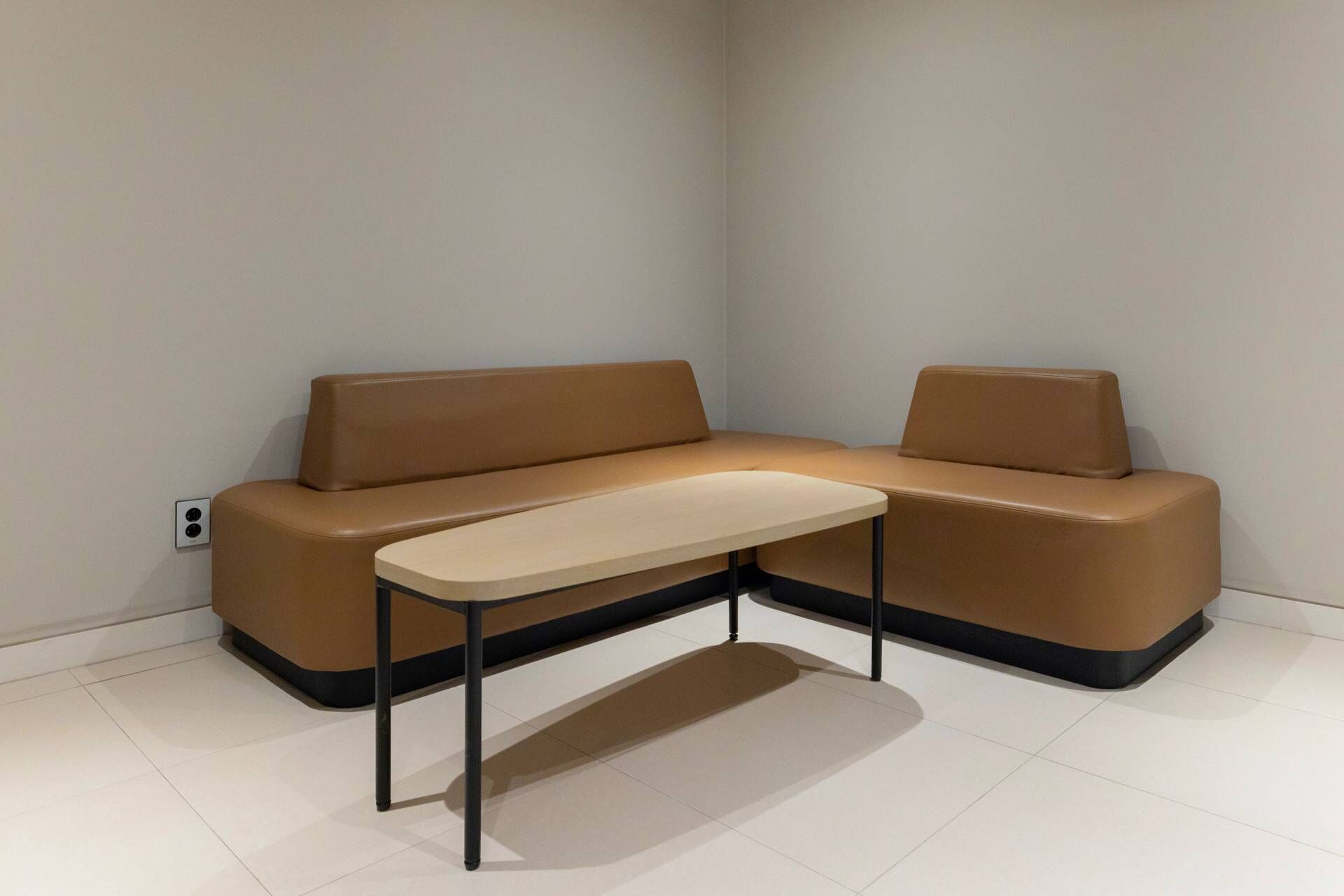 Un canapé d’angle assorti d’un fauteuil et d’une petite table dans une pièce au style minimaliste.
