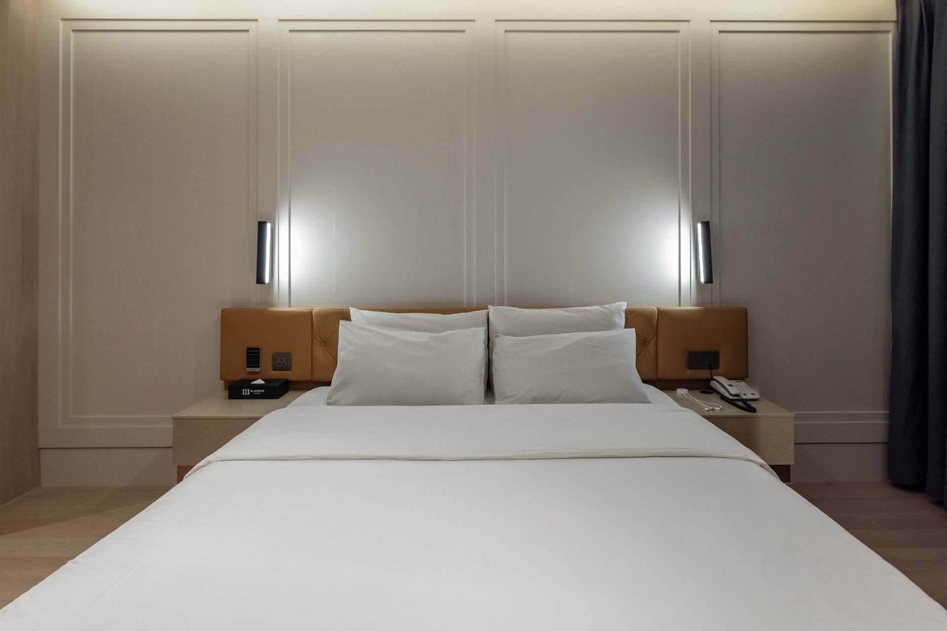 Una habitación de hotel con una cama grande, dos mesitas de noche y lámparas fijadas a la pared.