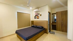 A bedroom with a bed, a wardrobe, and a ceiling fan. - C Suites 589 Richfield (Bengaluru)