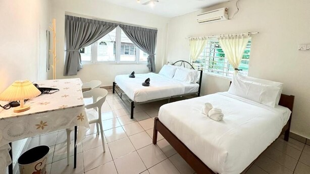 A hotel room with two single beds, a desk with a lamp, a chair, and a ceiling fan. - K INN 55 (George Town)