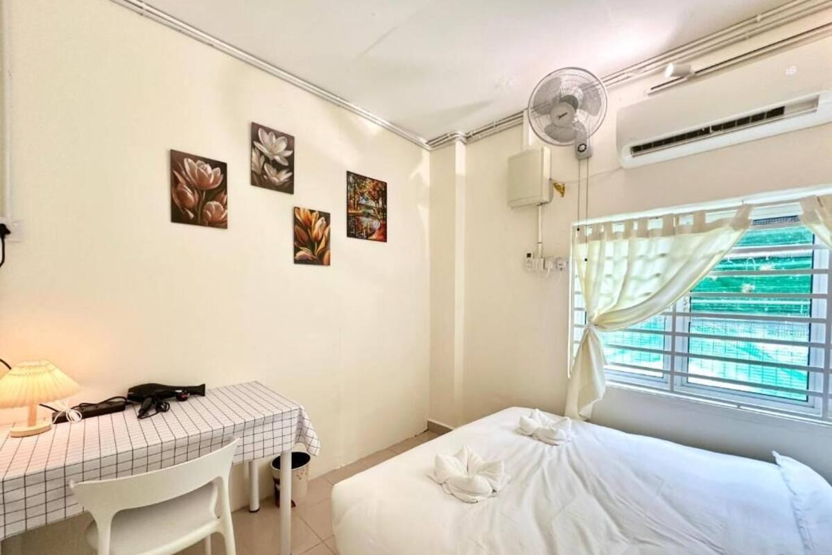 A hotel room with a bed, a desk with a chair, a table lamp, and wall art.