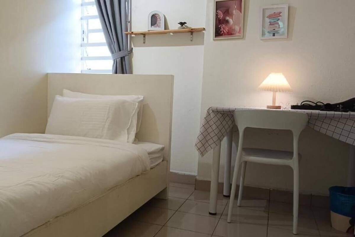 A small, neatly arranged bedroom with a bed, a desk, and a chair.