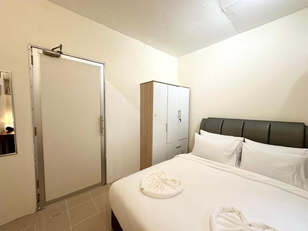 A hotel room with a bed, a wardrobe, and a shower area.