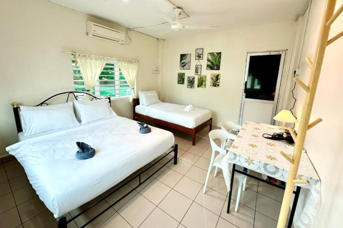 A room with two beds, a small table with chairs, a desk with a lamp, and wall art.