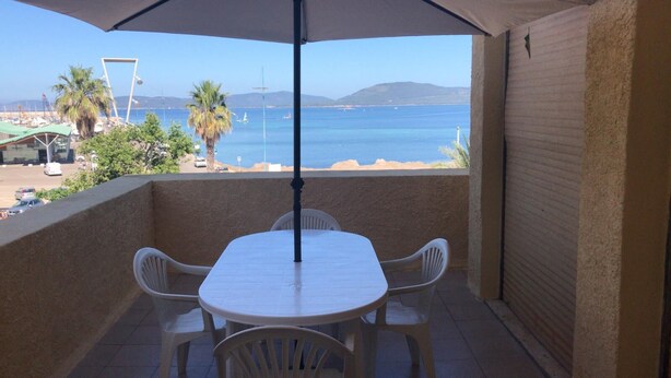 Un balcone con tavolo e sedie, vista su una spiaggia e il mare.
