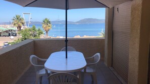 Ein Balkon mit Tisch und Stühlen mit Blick auf einen Strand und das Meer.