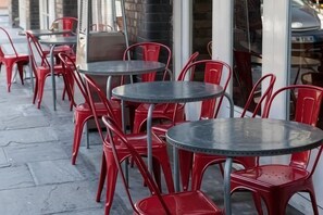 Espace extérieur aménagé avec des chaises rouges et des tables rondes.