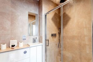 A bathroom with a glass shower enclosure, a sink, and a mirror. - One Bed Serviced Apt Near Holborn in Chancery Lane (London)