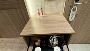 Una kitchenette compacta con estufa integrada, dos tazas, palillos y una bandeja con botellas de té.