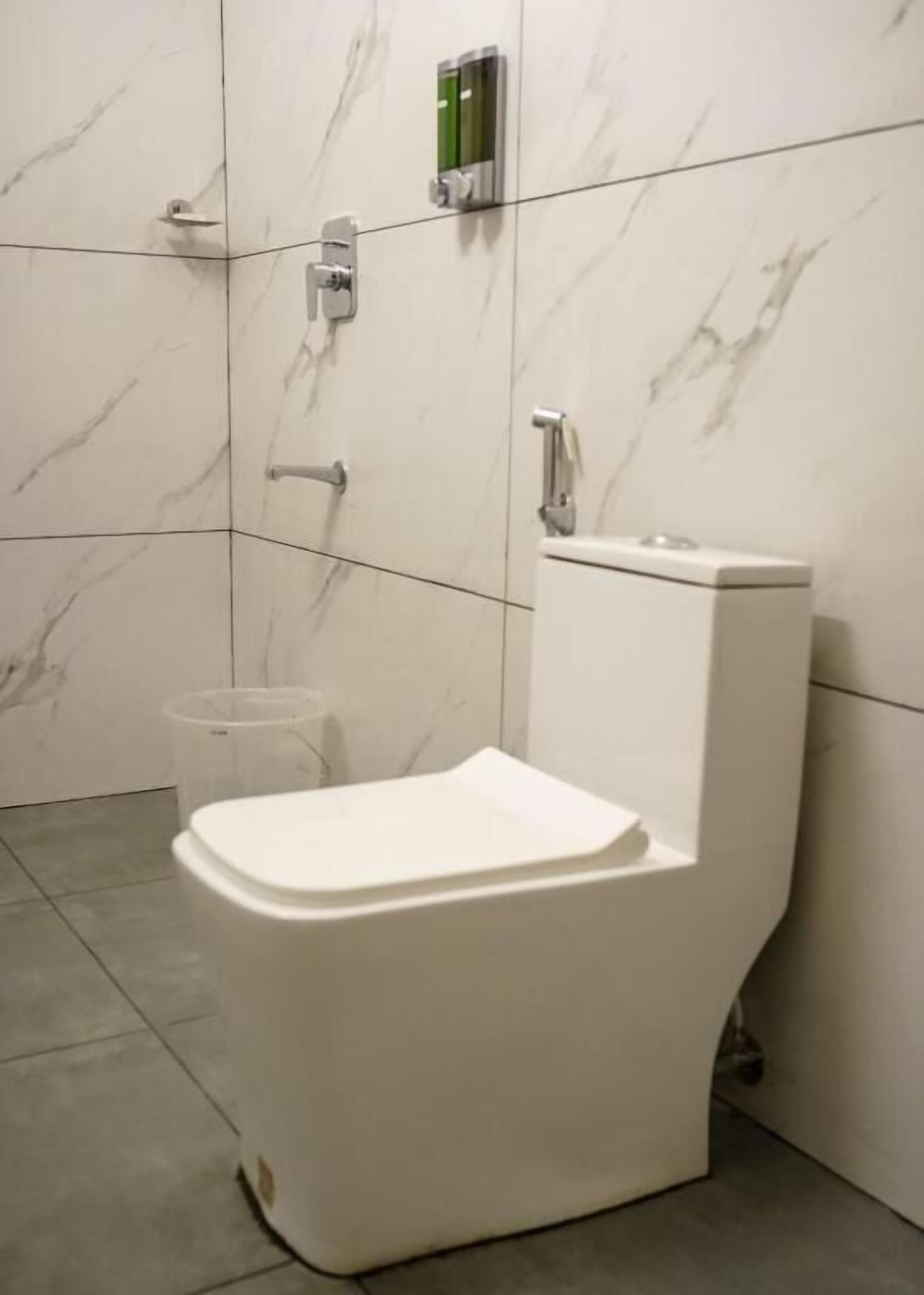 Ein modernes Badezimmer mit Toilette, Marmorwänden und einer kleinen Mülleimer.