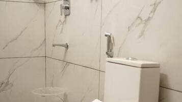 Ein modernes Badezimmer mit Toilette, Marmorwänden und einer kleinen Mülleimer.