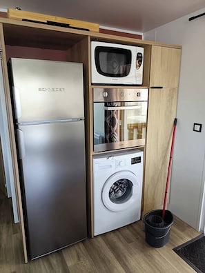 Eine kompakte Küche mit integriertem Kühlschrank, Backofen, Mikrowelle und Waschmaschine.